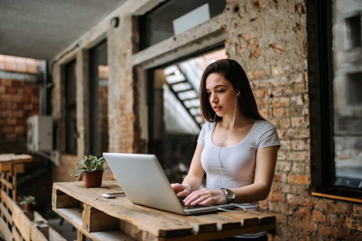 Woman Blogger Using Laptop And Wearing Earphones