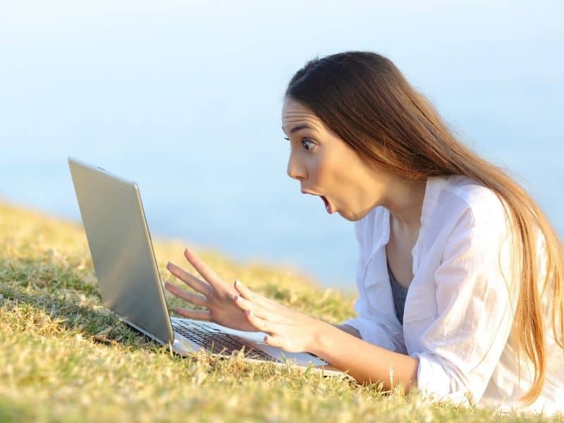 Woman Shocked Looking At A Laptop On Grass