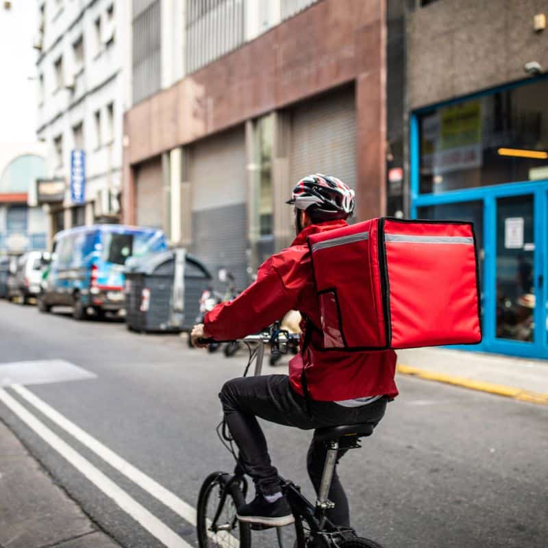 Man In Red Clothing Delivering Food On A Bicycle