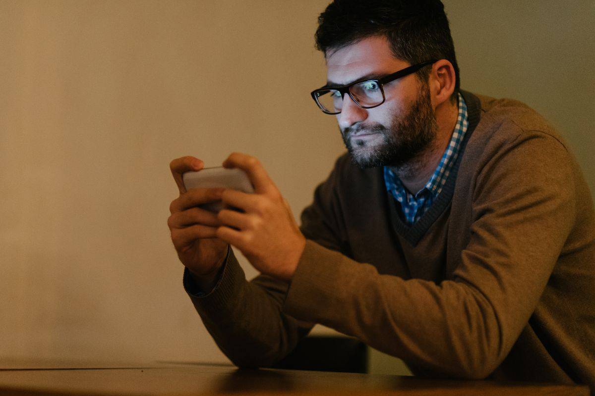 man looking at blue light on a smartphone screen