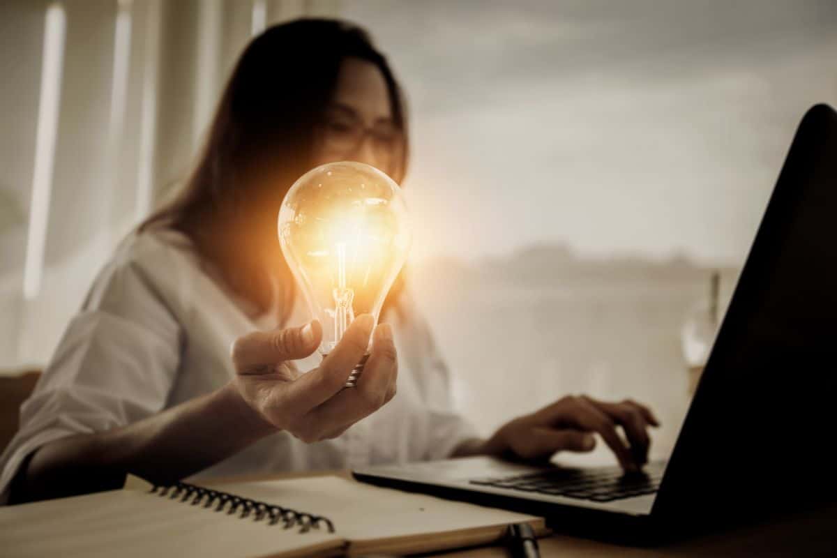 woman on laptop holding lightbulb